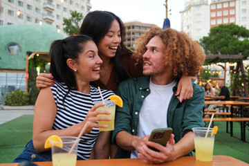 Three friends are having drinks and chatting at an outdoor bar, enjoying their time together
