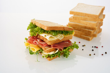 Delicious sandwich stacked with fresh ingredients and slices of bread on a white surface