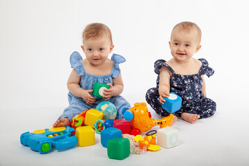 Happy Babies Playing with Colorful Educational Toys on White Background &ndash; Smiling Infants in Stylish Outfits Engaged in Learning and Fun, Perfect for Parenting, Early Childhood, or Toy Ads