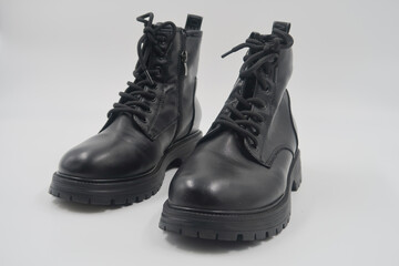 Pair of black leather lace-up ankle boots with rugged soles, isolated on a white background.