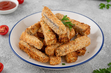 Baked crispy eggplant sticks served with tomatoes sauce on a plate on a gray concrete background. Vegetarian healthy dish. Selective focus