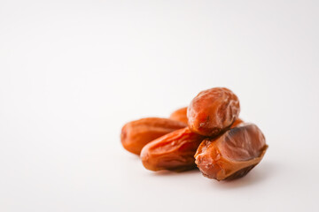 Top view of five dried dates arranged diagonally on a light cream background. Simple organic food layout, perfect for packaging, healthy eating, or clean food concepts