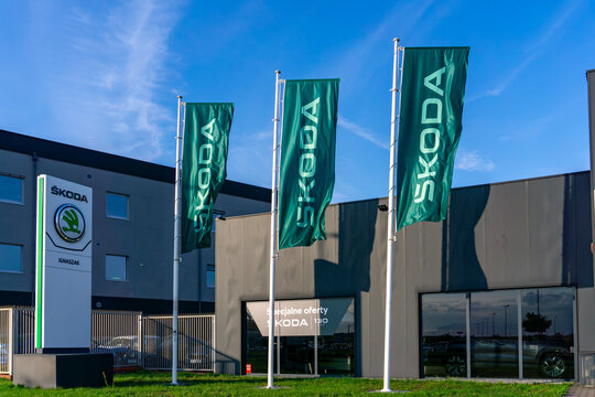 koda Ignaszak car dealership with visible sign, three green brand flags, modern building and glass windows, set against a blue sky background.