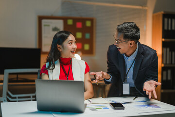 Asian businesspeople discussing over laptop in office at night