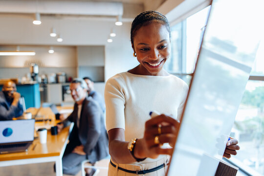 Woman writing on a whiteboard in a business meeting setting