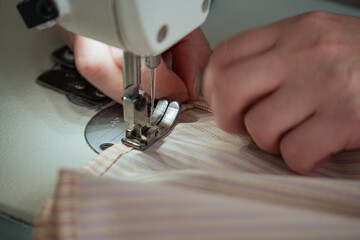 A seamstress works on a production sewing machine at an enterprise, sewing bed linen