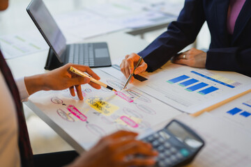 Business colleagues discussing new business plan using colorful sticky notes, analyzing financial charts and graphs