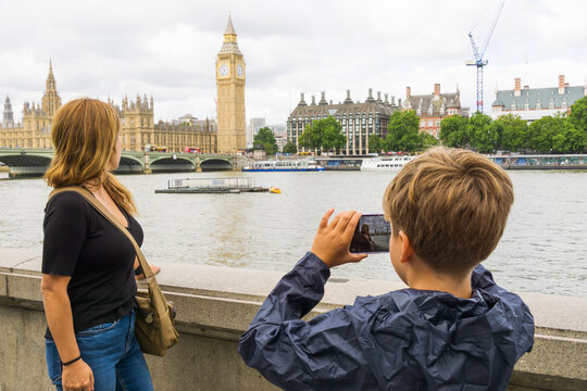Young boy photographing his mother with Big Ben and Houses of Parliament in the background.