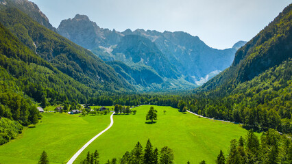 Aerial panoramic view of Logar Valley in Slovenia with vibrant green alpine meadows and dramatic mountain peaks of the Kamnik-Savinja Alps, a top destination for hiking and nature travel lovers