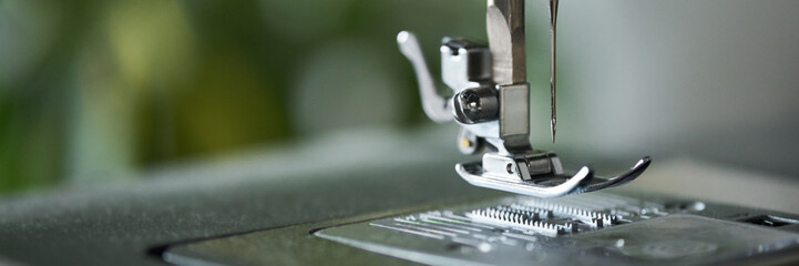 Close up showing metal presser foot and needle of sewing machine positioned above needle plate, focusing on mechanical details and precision components in textile equipment