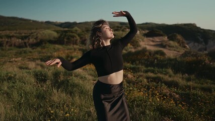 A young female dancer in trendy attire performs a beautiful contemporary dance in a scenic outdoor setting, expressing freedom and elegance.