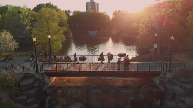 People enjoy the sunset from a bridge in La Fontaine Park. They are relaxing and taking in the scenery on a beautiful evening.  Montreal, Quebec, Canada. 22 May 2025.
