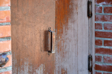 Rustic wooden door with an iron handle in a brick wall setting