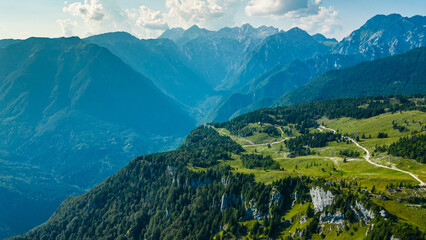 Aerial panoramic view of Velika Planina in Slovenia featuring vast green alpine pastures dotted with traditional mountain huts, set against the stunning backdrop of the Kamnik-Savinja Alps © Viktor