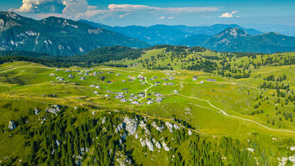 Aerial panoramic view of Velika Planina in Slovenia featuring vast green alpine pastures dotted...