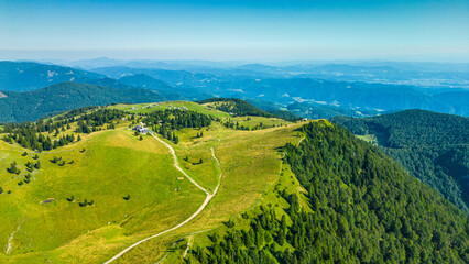 Aerial panoramic view of Velika Planina in Slovenia featuring vast green alpine pastures dotted...