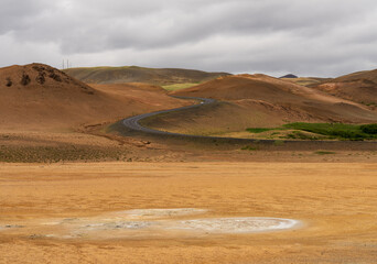 Geothermal activity creates a surreal landscape at Hverir in Namafjall, Iceland with winding roads through mud pots and steam vents