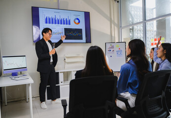 Asian businessman presenting marketing data to colleagues in meeting room