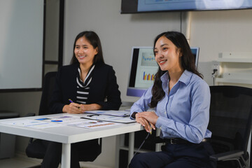 Businesswomen smiling and discussing marketing data during a meeting