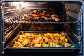 Ready-made chicken tabaka with potato cookies in the oven.