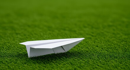 White paper airplane on green grass isolated on green  background