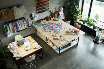 High angle view showing sewing studio workspace with fabric swatches, sewing machine, mannequin,...