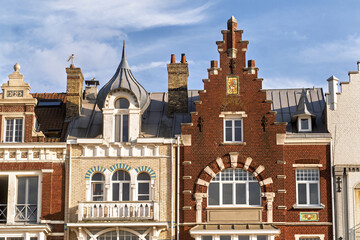 row of ornate historic townhouses with distinct architectural styles. The scene captures the charm of coastal architecture in Dunkirk, France