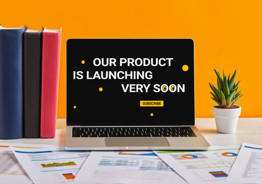 Laptop Showing Coming Soon Product Launch Page with Business Reports and Books