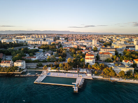 Aerial drone photo of Zadar Diving Board and Bazen Kolovare in Croatia, with the Adriatic Sea and expansive sunset sky creating a serene coastal scene during golden hour.  