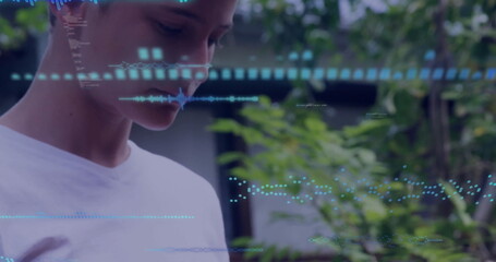 Scanning preteen boy focusing on floating blue data overlays in garden courtyard, copy space