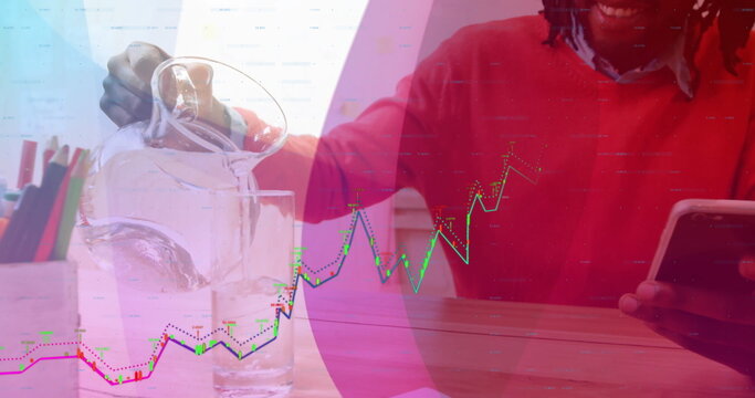 Pouring water into glass, man in red sweater holding tablet at desk, colored pencils, graph overlay - Powered by Adobe