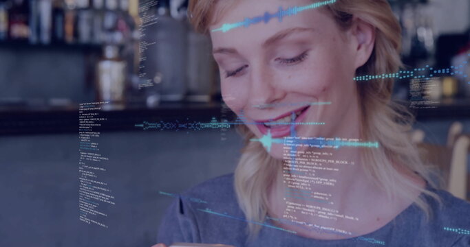 Smiling woman holding smartphone and viewing holographic code overlays at cafe counter, grey top