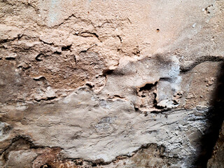 Weathered brown concrete wall with a rough, grungy texture and peeling paint