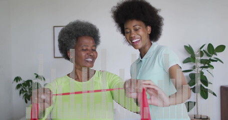 Stretching mother and daughter pulling red resistance band in home living room, with potted plants