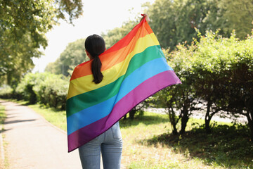 LGBT concept. Woman with rainbow flag outdoors, back view