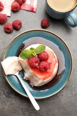 Delicious panna cotta with berries, sauce and mint on grey textured table, flat lay