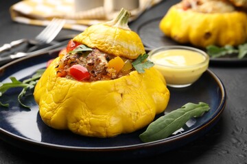 Tasty stuffed pattypan squash with sauce on black table, closeup
