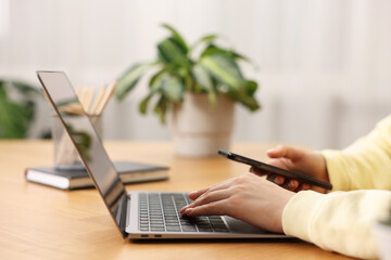 Copywriter using laptop at wooden table indoors, closeup