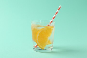 Sparkling water with orange slices in glass on turquoise background