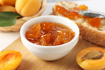 Tasty apricot jam and fresh fruits on white table, closeup