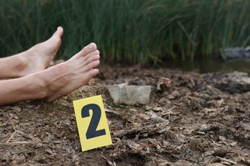 Forensic expertise. Crime scene with dead man's body and marker outdoors, closeup. Space for text