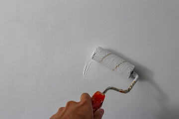 Paint roller with orange handle placed against white wall showcasing home improvement and interior decoration tools