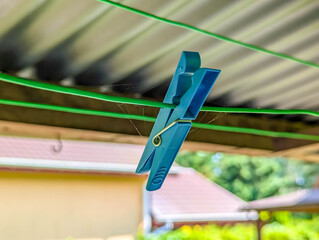 Blue plastic clothespins securely clipping white fabric on outdoor washing line during sunny summer day