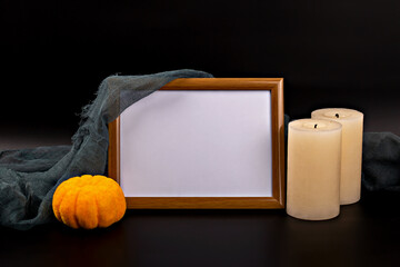 Halloween. Mockup. Wooden frame featuring blank space is surrounded by an orange pumpkin and two candles, creating cozy Halloween atmosphere with dark background and soft textures enhancing scene