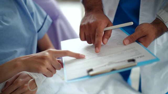 Close up at patient and doctor hands while consulting and examing disease on
medical chart clipboard for discussion the treatment results, medical clinic or
hospital and healthcare service concept.
