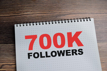 Concept of 700K Followers - reaching 700.000 followers on social media platform write on book isolated on Wooden Table.