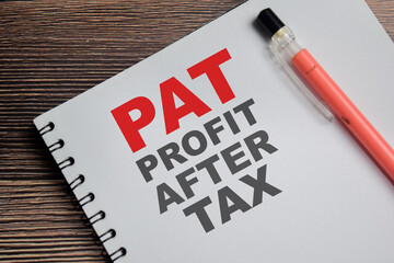 Concept of PAT - Profit after Tax write on book isolated on Wooden Table.