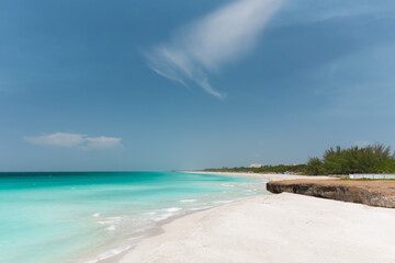 Varadero,Cuba, gorgeous inviting view on white sand majestic beach with old, naturally formatted volcanic cliff near the ocean shore,deep blue sky,sunny day