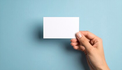 Obraz premium Hand holding blank white card on light blue background