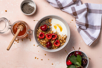 Bowl of oat granola with Greek yogurt, cherries, chia seeds and honey. Rolled oats with berries. Muesli for healthy breakfast. Home cooking. Fitness, diet concept. Top view.